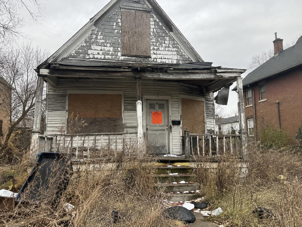A distressed, boarded-up house — the kind of property Rocky Luv Estates buys
